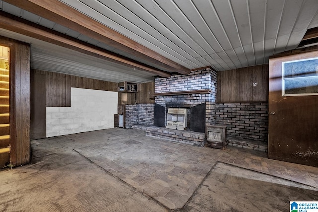 unfurnished living room featuring a brick fireplace and wooden walls