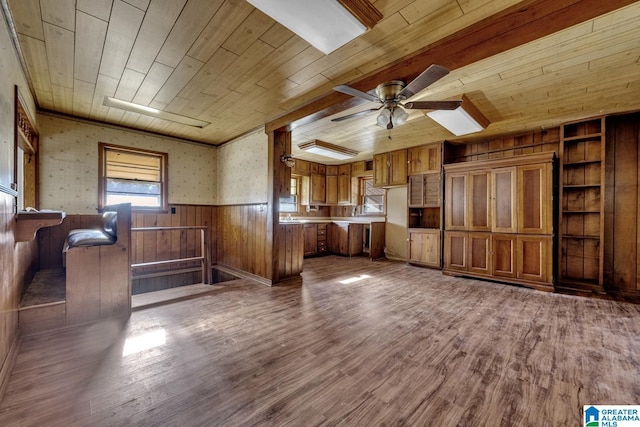 unfurnished living room with a wainscoted wall, wood ceiling, a ceiling fan, and wood finished floors