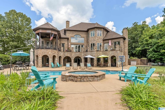 rear view of property featuring a balcony, a patio, and a pool with hot tub