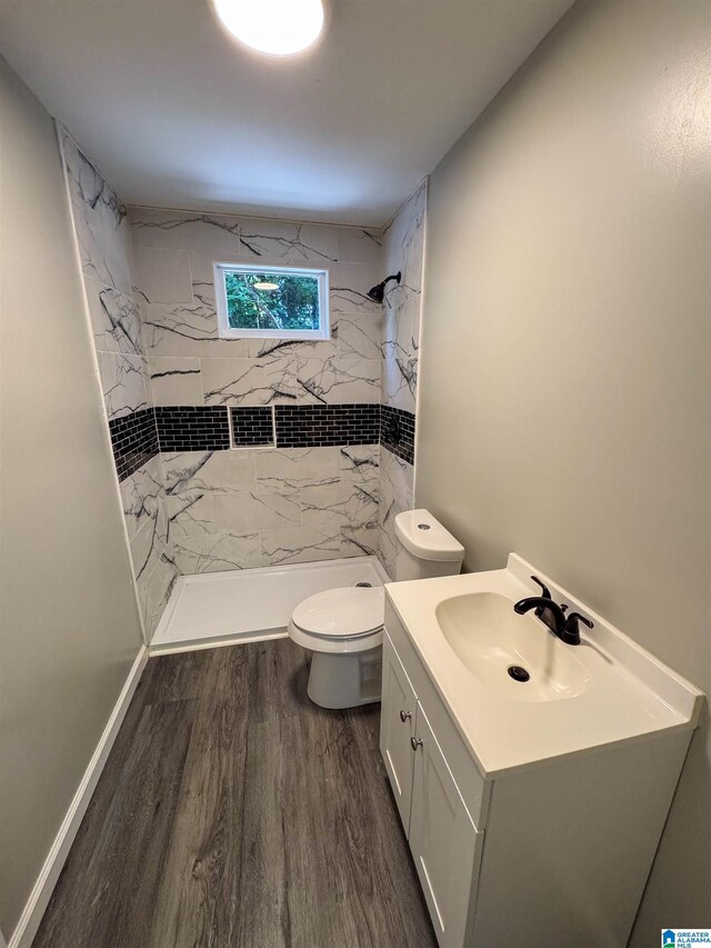 full bathroom featuring a stall shower, toilet, vanity, wood finished floors, and baseboards