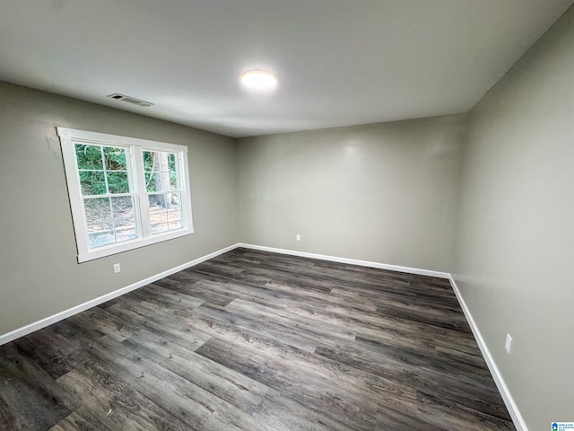 empty room featuring dark wood-type flooring, baseboards, and visible vents