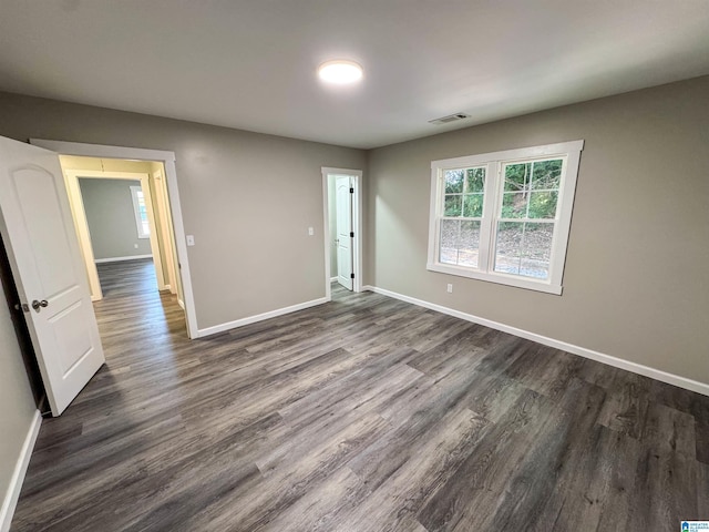 unfurnished room featuring dark wood-type flooring, baseboards, and visible vents