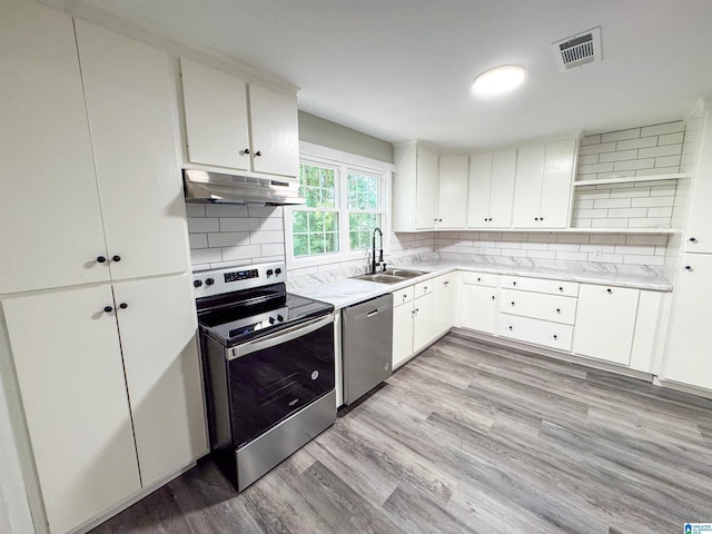 kitchen with visible vents, stainless steel appliances, under cabinet range hood, a sink, and backsplash