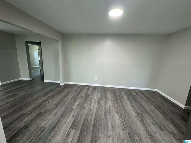 empty room featuring dark wood-style floors and baseboards