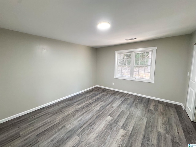 unfurnished room with baseboards, visible vents, and dark wood-style flooring