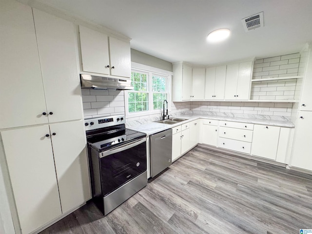 kitchen with light wood-type flooring, tasteful backsplash, stainless steel appliances, and sink