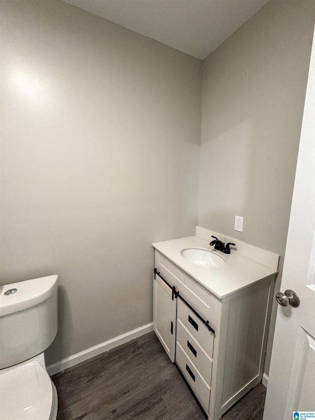 bathroom with hardwood / wood-style floors, toilet, and vanity