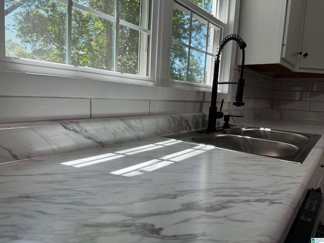 kitchen with concrete flooring, a healthy amount of sunlight, sink, and white cabinets