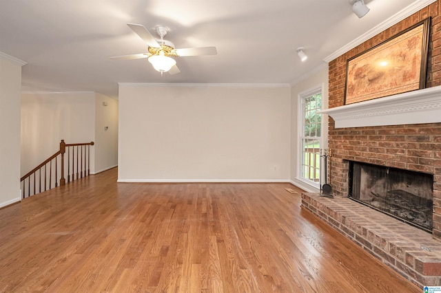 unfurnished living room with crown molding, light wood-type flooring, and a brick fireplace