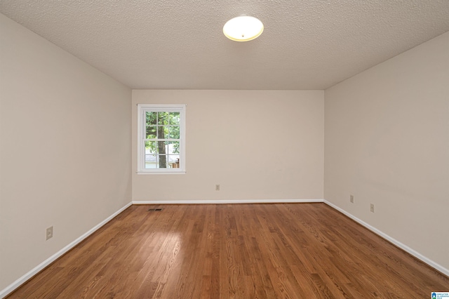 empty room featuring a textured ceiling and hardwood / wood-style flooring