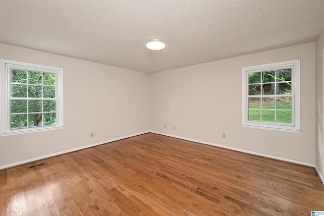 spare room featuring wood-type flooring and a textured ceiling