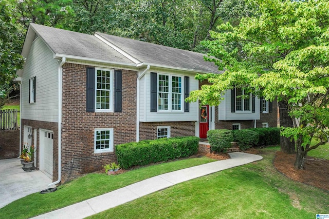 raised ranch featuring a garage and a front lawn