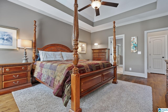 bedroom featuring ceiling fan, a tray ceiling, dark wood-type flooring, and baseboards