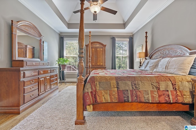 bedroom featuring ornamental molding, a raised ceiling, light wood finished floors, and a ceiling fan