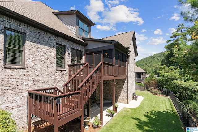 exterior space with a deck, a fenced backyard, a sunroom, stairs, and a lawn