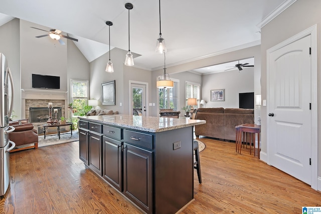 kitchen with a fireplace, hanging light fixtures, open floor plan, a kitchen island, and a kitchen breakfast bar