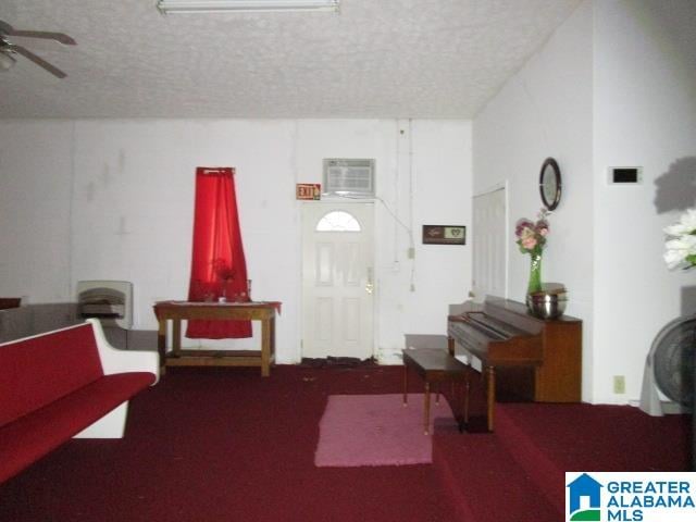 interior space featuring a textured ceiling, ceiling fan, and a wall mounted air conditioner