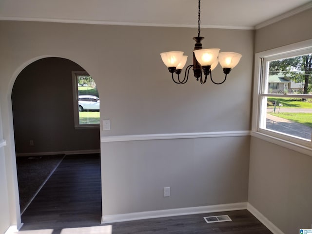 unfurnished dining area featuring dark hardwood / wood-style floors, a healthy amount of sunlight, a chandelier, and ornamental molding