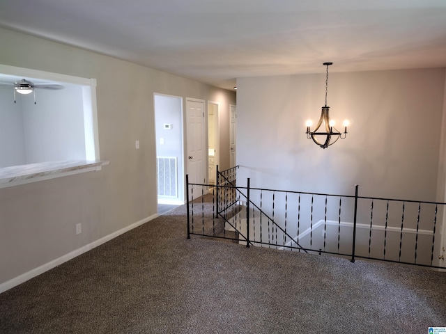 carpeted spare room featuring ceiling fan with notable chandelier