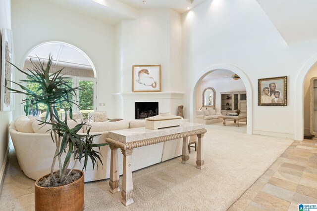 living room featuring ceiling fan, light tile patterned flooring, and a high ceiling