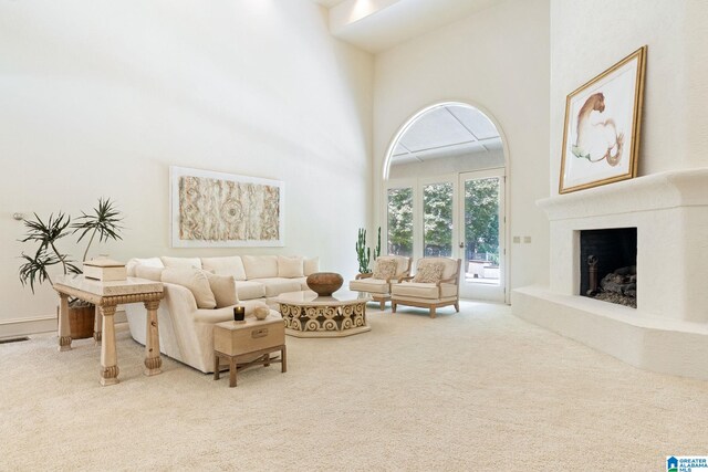 carpeted living room featuring a high ceiling and a premium fireplace