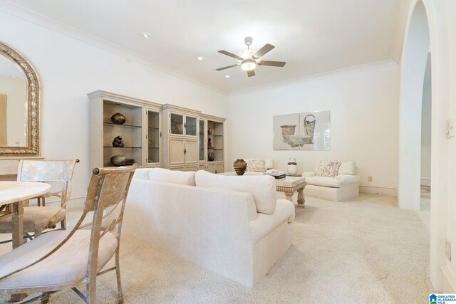 living room with ceiling fan, light carpet, and crown molding