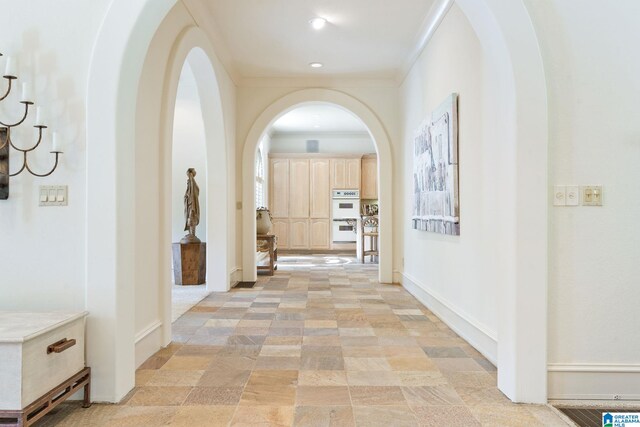 corridor with light tile patterned flooring and ornamental molding