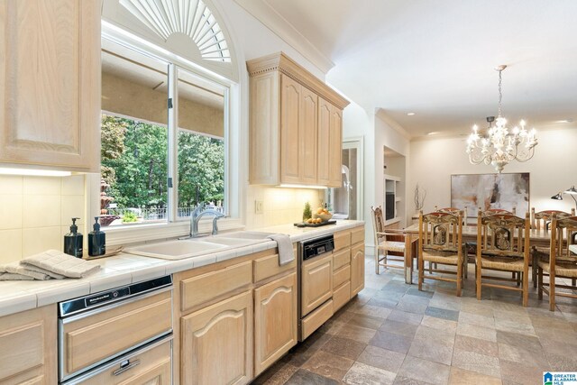 kitchen with light brown cabinets, decorative backsplash, tile counters, dishwasher, and sink