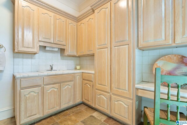 kitchen with tasteful backsplash, light brown cabinetry, tile patterned flooring, tile countertops, and sink