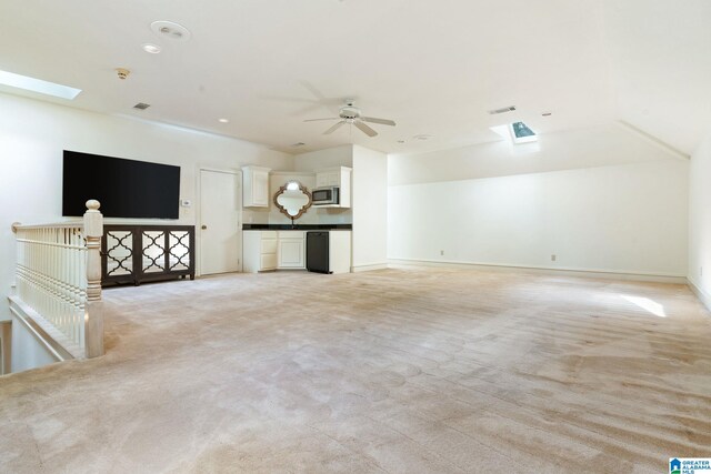 unfurnished living room featuring ceiling fan, a skylight, and light colored carpet