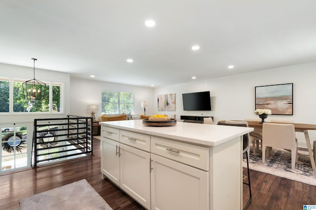 kitchen featuring dark wood-type flooring, a kitchen bar, a center island, and a notable chandelier