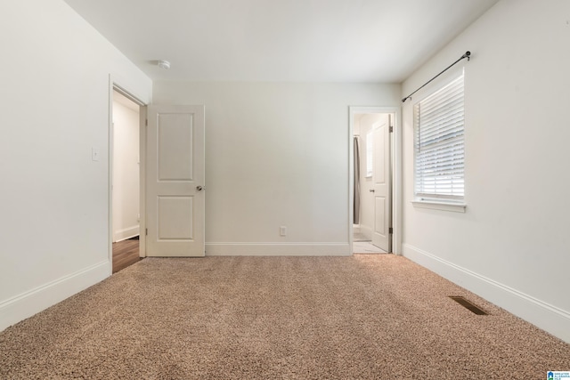 unfurnished bedroom featuring light carpet and ensuite bath