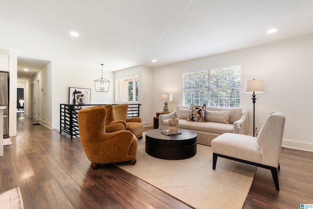 living room featuring a healthy amount of sunlight, a notable chandelier, and dark hardwood / wood-style flooring