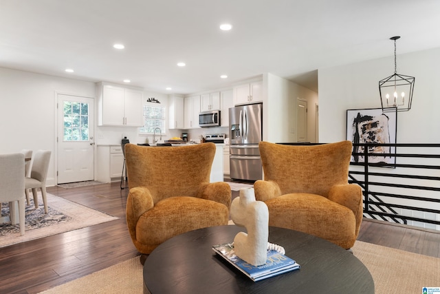 living room featuring dark wood-type flooring, a chandelier, and sink