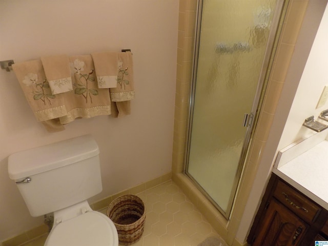 bathroom featuring toilet, a shower stall, baseboards, and tile patterned flooring