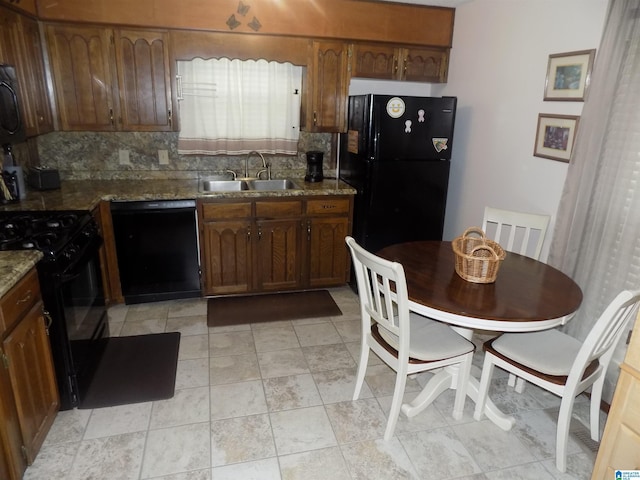 kitchen with black appliances, light stone counters, a sink, and tasteful backsplash