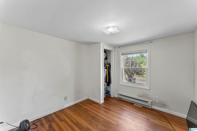 empty room with baseboard heating and hardwood / wood-style flooring