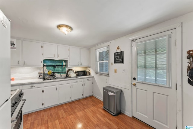 kitchen featuring sink, light wood-type flooring, white fridge, electric stove, and white cabinets