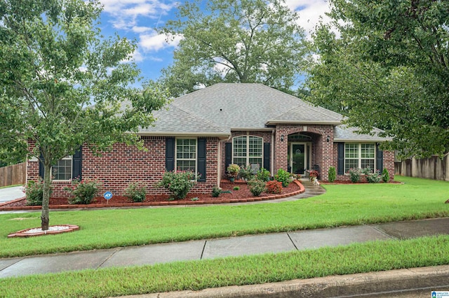 single story home featuring brick siding, fence, a front lawn, and roof with shingles