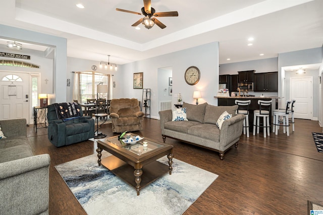 living room with a raised ceiling, ceiling fan, and dark hardwood / wood-style floors