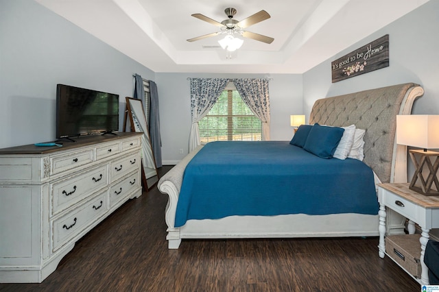 bedroom with a raised ceiling, ceiling fan, and dark hardwood / wood-style flooring