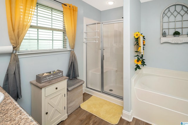 bathroom with wood-type flooring, separate shower and tub, and vanity