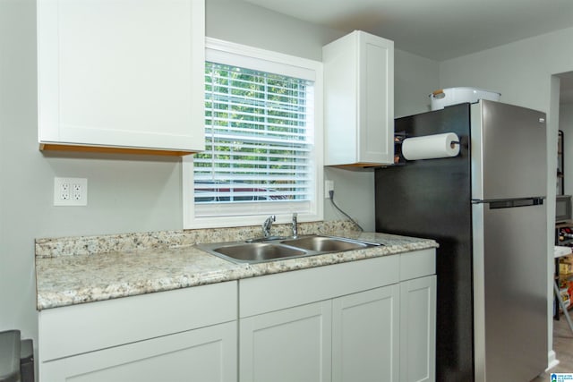 kitchen featuring white cabinetry, sink, and stainless steel refrigerator