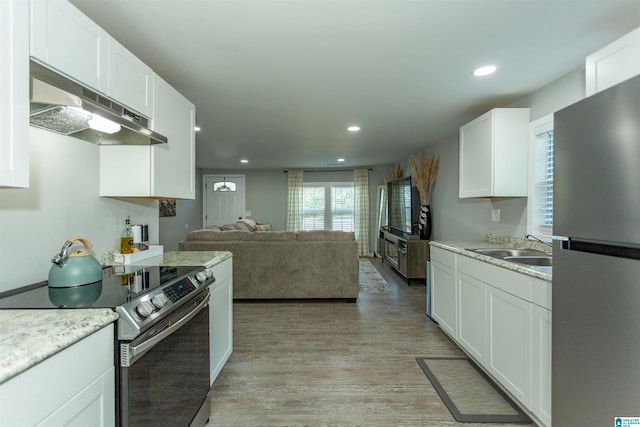 kitchen with stainless steel appliances, light hardwood / wood-style flooring, sink, wall chimney range hood, and white cabinets