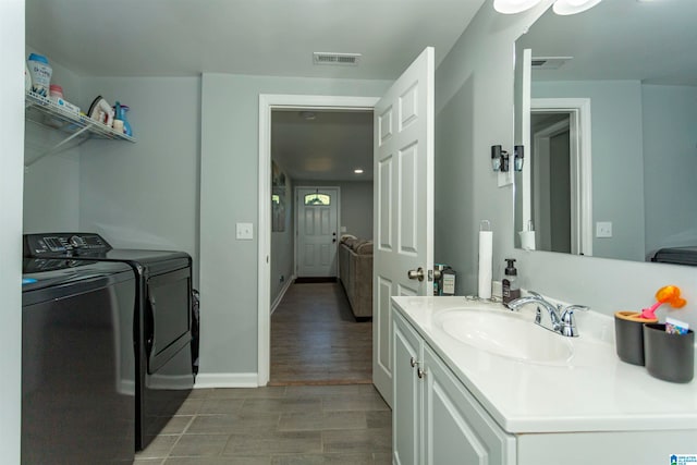 laundry room featuring washer and dryer, sink, and wood-type flooring