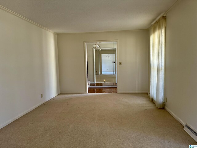 spare room with a baseboard heating unit, crown molding, light colored carpet, and a chandelier