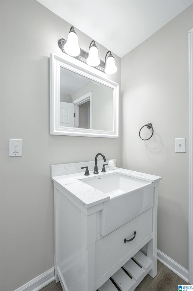 bathroom featuring baseboards, wood finished floors, and vanity