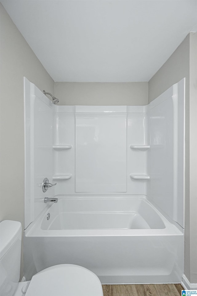 bathroom with tub / shower combination, toilet, and wood finished floors