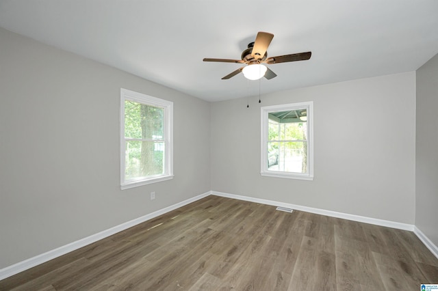 unfurnished room featuring ceiling fan, wood finished floors, visible vents, and baseboards