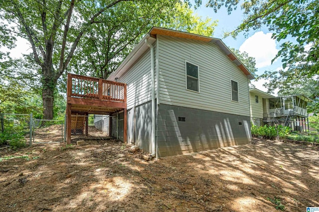 view of property exterior with a deck, a garage, fence, driveway, and a gate